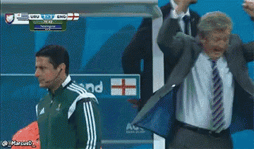 a man in a suit and tie stands in front of a scoreboard that says uruguay vs england