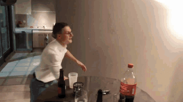 a bottle of coca cola sits on a table next to a man
