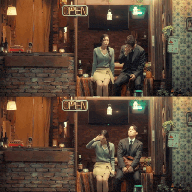 a couple sitting under an open sign in a restaurant