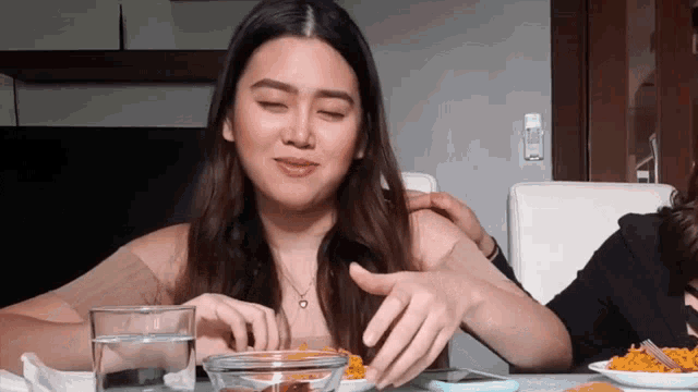a woman sitting at a table with a bowl of food
