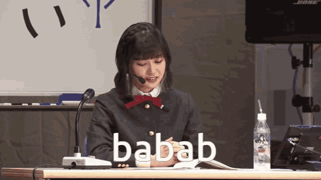 a woman sitting at a desk with the word babab on the table