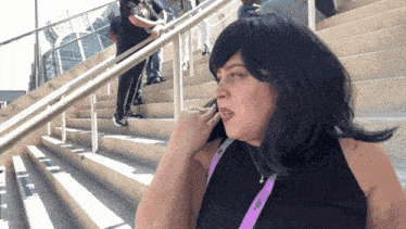 a woman talking on a cell phone with a lanyard around her neck that says ' a ' on it