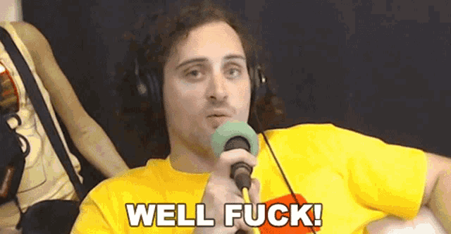 a man wearing headphones is holding a microphone and the words well fuck are above him