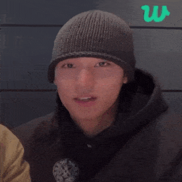 a young man wearing a black beanie and a black hoodie .