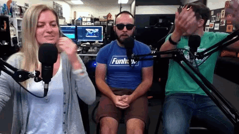 a man wearing a blue shirt that says funshow is sitting in front of a microphone