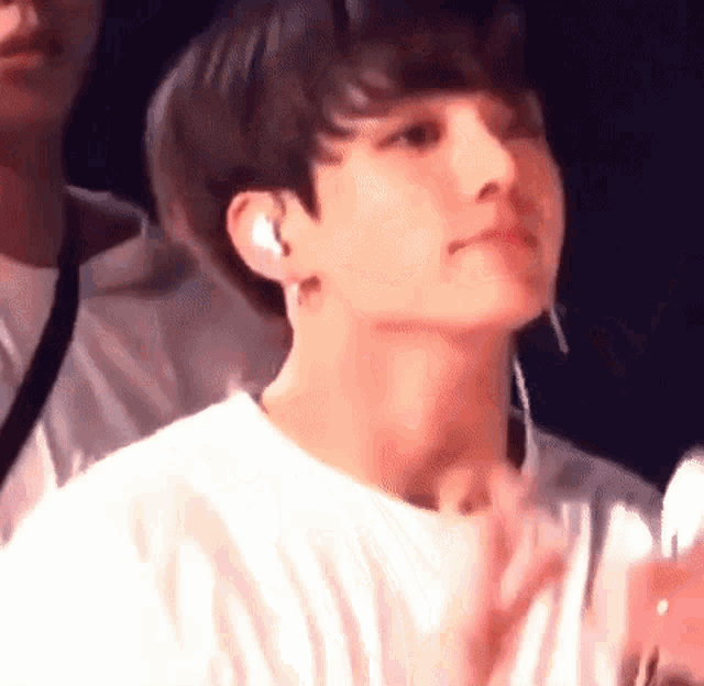 a close up of a person wearing a white shirt and earbuds .