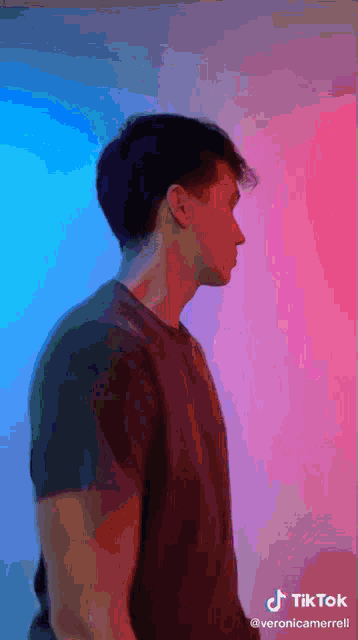 a man in a black shirt is standing in front of a pink and blue background with tiktok written in the corner