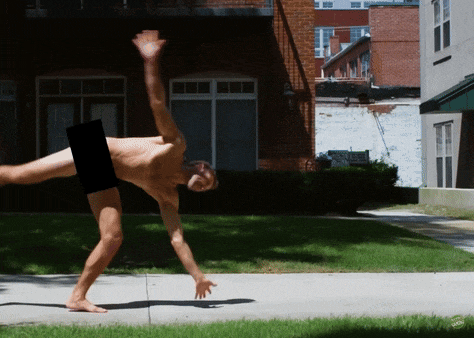 a naked man is doing a handstand on a sidewalk