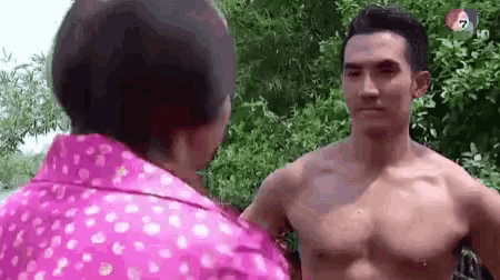 a shirtless man is standing next to a woman in a pink polka dot shirt .