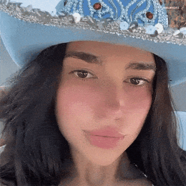 a close up of a woman wearing a blue cowboy hat .