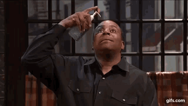 a man in a black shirt is holding a bottle of water in front of his face .