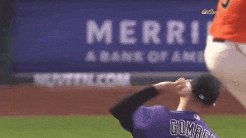 a baseball player in a purple uniform is throwing a baseball in front of a merri bank of america sign