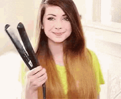 a woman with long hair is holding a hair straightener in her hand .
