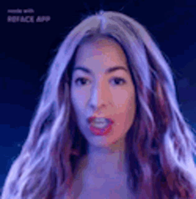 a woman with long purple hair is making a funny face in a dark room .