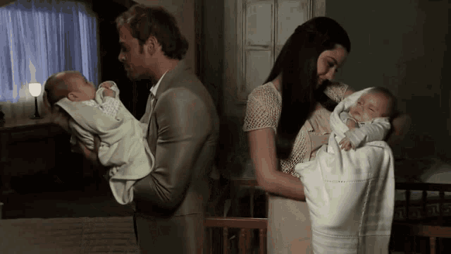 a man and woman holding two babies in a room
