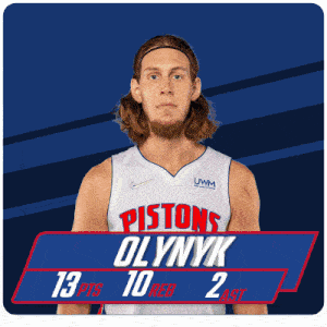 a man in a pistons jersey stands in front of a scoreboard