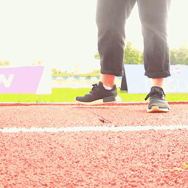 a person standing on a track with a sign that says ' n ' in the background