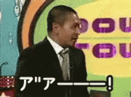 a man in a suit and tie is standing in front of a yellow sign that says you