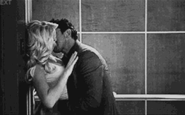 a black and white photo of a man and woman kissing in an elevator