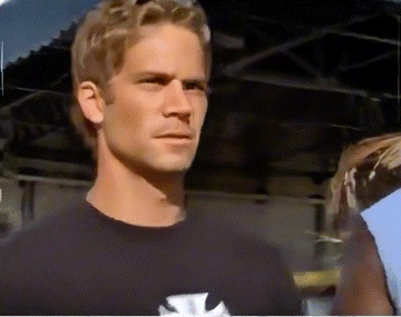 a man wearing a black shirt with a cross on it looks at the camera