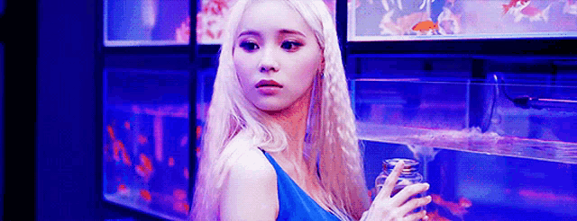 a woman in a blue dress is standing in front of a fish tank .