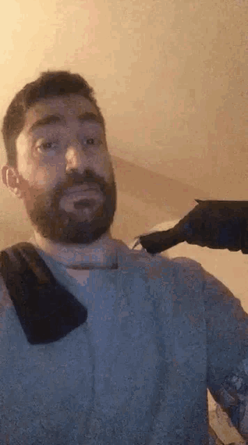 a man with a beard and a towel around his neck is holding a black object .