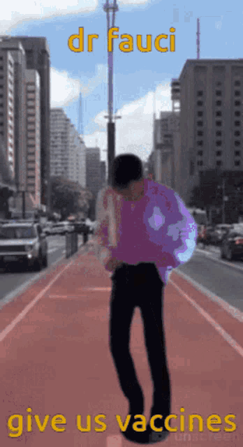 a man in a purple shirt is walking down a city street with the words dr fauci give us vaccines