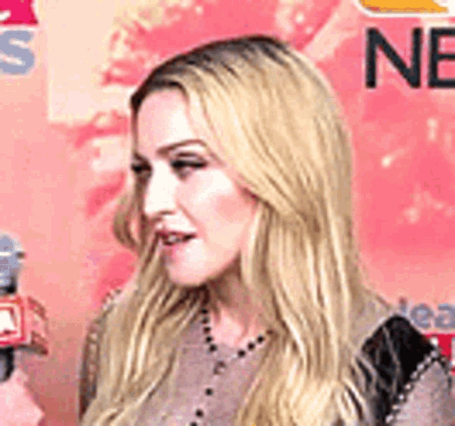 a woman is holding a microphone in front of a pink wall .