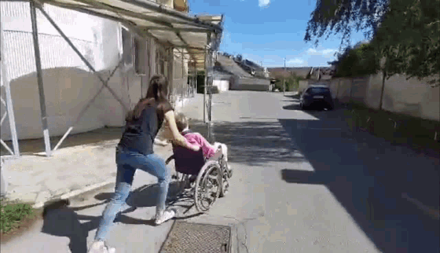 a woman pushing an elderly woman in a wheelchair down a street .
