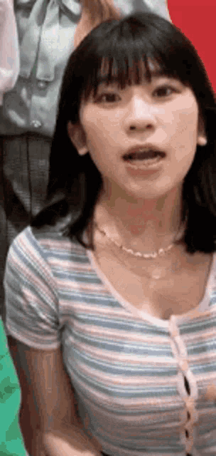 a woman in a striped shirt is making a funny face .