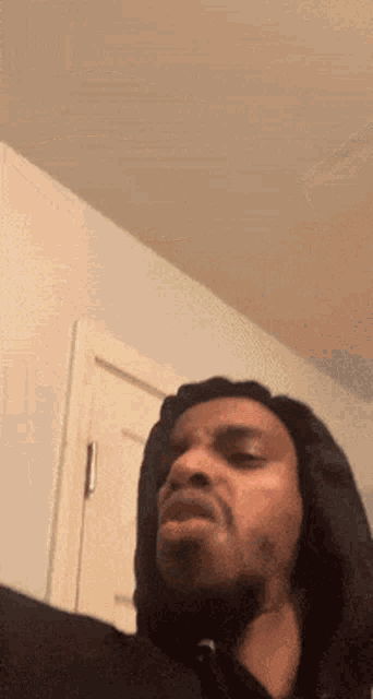 a man in a black hoodie is making a funny face in a room .