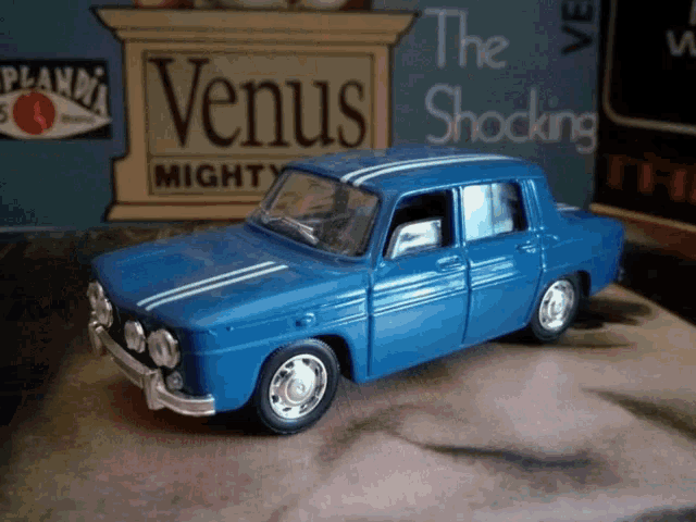 a blue toy car sits in front of a book called the shocking venus mighty