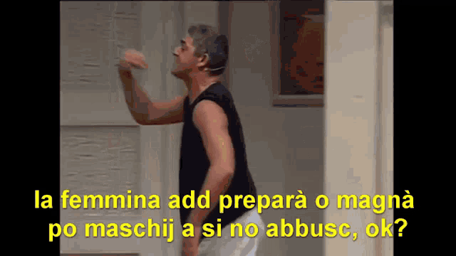 a man in a black tank top stands in front of a sign that says la femmina