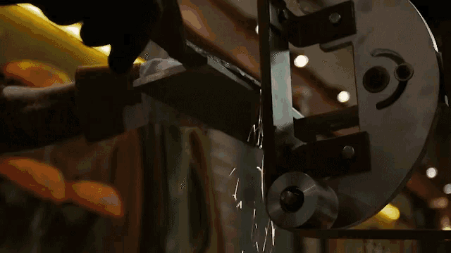 a person is cutting a piece of metal with a saw