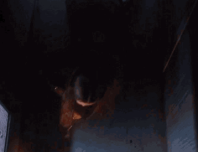 a person is hanging upside down in a dark room with a fire coming out of the ceiling .