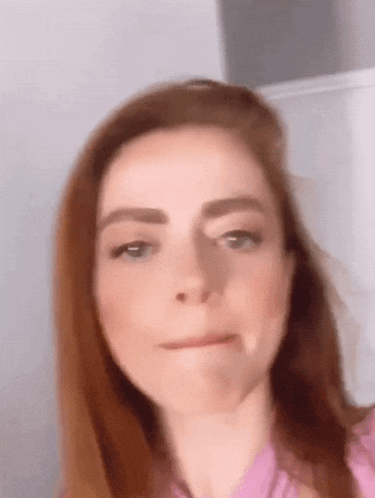 a woman with red hair and blue eyes is making a funny face .