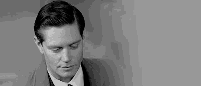a man in a suit and tie is looking down at something .