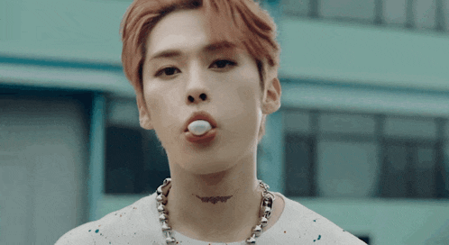 a young man with a tattoo on his neck is blowing a bubble gum