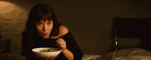 a woman is eating a bowl of food in a dark room .