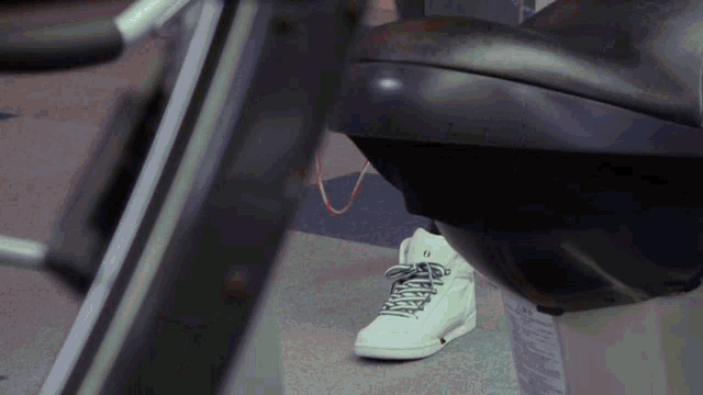 a person wearing a pair of white high top sneakers with black laces