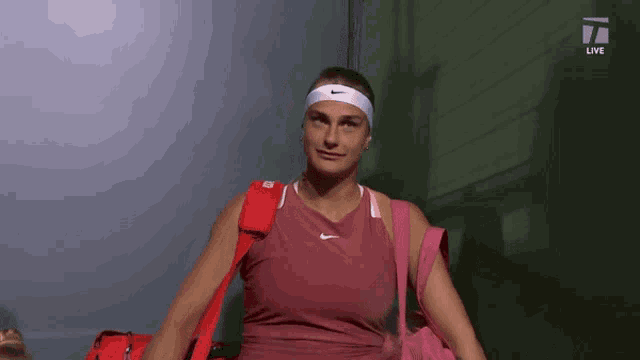a woman wearing a nike headband and a pink bag