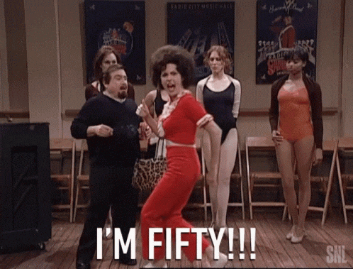 a woman in a red outfit is dancing in front of a group of women and says i 'm fifty !!