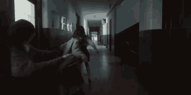 a group of people are walking down a hallway with their arms outstretched