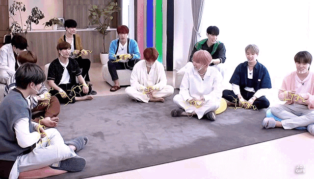 a group of young men are sitting in a circle on the floor playing a game