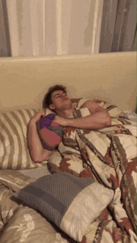 a man is laying on a bed with a striped blanket