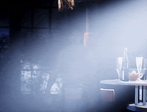 a table with glasses and a bottle on it in a dark room