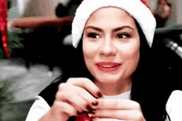 a woman wearing a santa hat is holding a candy cane in her hand .