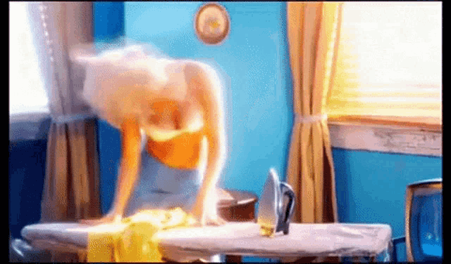 a woman is ironing clothes on an ironing board in front of a window