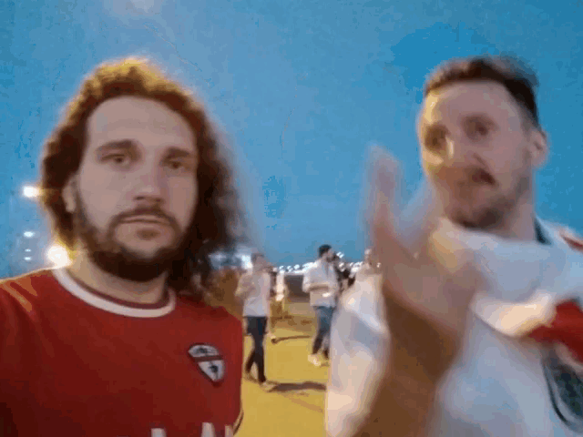 two men standing next to each other with one wearing a red shirt that says ' gd ' on it
