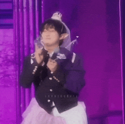 a man is standing on a stage wearing a fairy costume and holding a microphone .